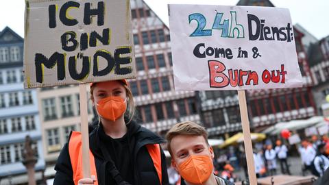 Eine Frau und ein Mann halten bei einer Demonstration selbstgeschriebene Schilder in den Händen.