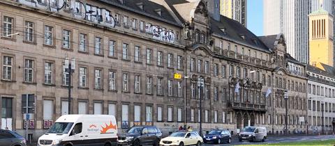 Foto von einem großen historischen Gebäude, das an einer großen städtischen Straße (Frankfurt) steht.