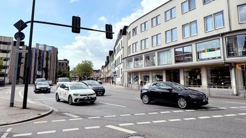 Straße mit vier Autospuren, darauf mehrere Autos, die an einer Ampel anfahren.