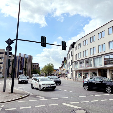 Straße mit vier Autospuren, darauf mehrere Autos, die an einer Ampel anfahren.