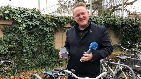 hr-Reporter Jonas Schulte mit Fahrrad, Mikrophon und Smartphone