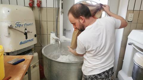 Bäckermeister Peter Seidl schüttet Mehl in eine große Edelstahlschüssel.