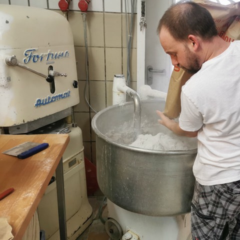Bäckermeister Peter Seidl schüttet Mehl in eine große Edelstahlschüssel.