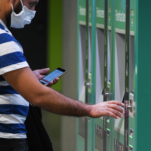 Ein Mann steht an einem Ticketautomaten des ÖPNV. Auf dem Automat sind Piktogramme der verschiedenen Verkehrsmöglichkeiten zu sehen.