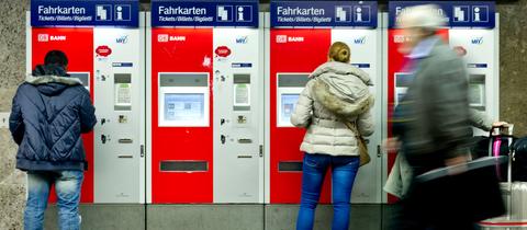Zwei Menschen stehen an Ticketautomaten der Deutschen Bahn. 