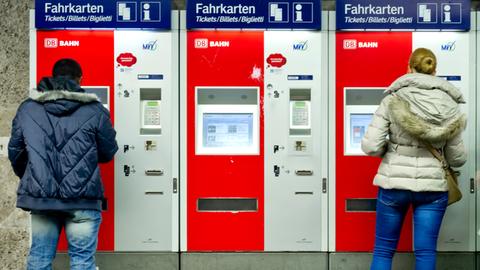 Zwei Menschen stehen an Ticketautomaten der Deutschen Bahn. 