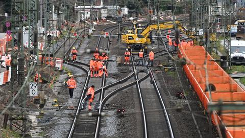 Auf Bahngleisen sind Bauarbeiter unterwegs.