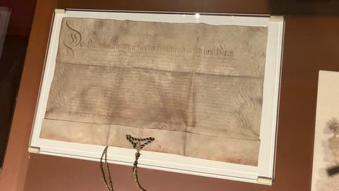 Ein altes Schriftstück in einer Glasvitrine: die Einbürgerungsurkunde der Stadt Frankfurt für Benjamin Metzler aus dem Jahr 1674
