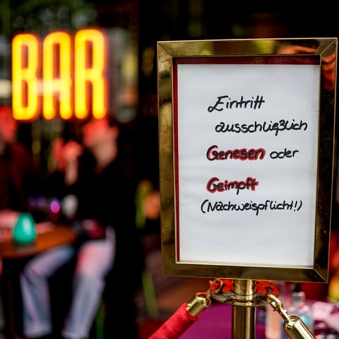 "Eintritt ausschließlich genesen oder geimpft" steht auf einem Schild vor eine Bar.