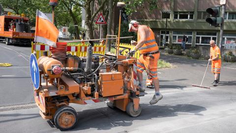 Männer in orangenen Baustellenanzügen richten eine Baustelle ein.