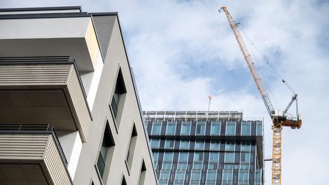 Ein Kran steht an einer Baustelle für Büros. Im Vordergrund ist ein Neubau mit Wohnungen zu sehen. 