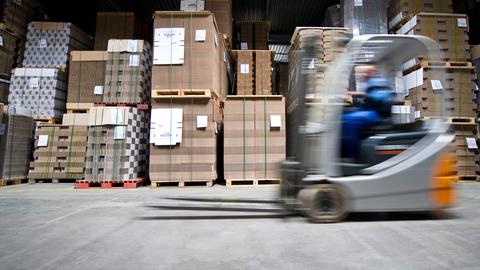 Ein Mann fährt mit einem Gabelstapler durch das Lager eines Logistikbetriebs