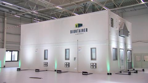 Ein weißer Container mit der Aufschrift "Biontech" steht in einer Gewerbehalle.