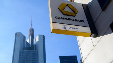 Vorne das Logo der Commerzbank, links die Konzernzentrale in Frankfurt 