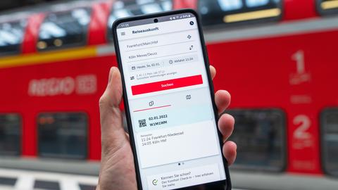 Smartphone-Bildschirm mit DB-Navigator App, im Hintergrund Regionalbahn.