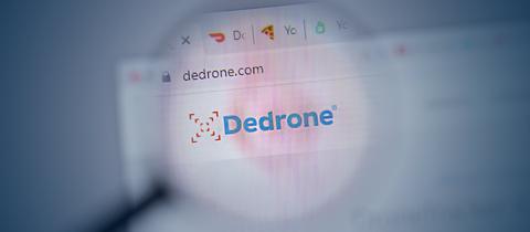 Foto eines Browserfensters, in welchem "DeDrone" steht. Drüber liegt unscharf eine Lupe. Das Bild verdunkelt sich nach außen, in der Mitte ist es heller.