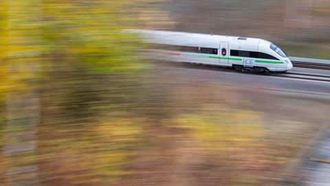 Ein ICE der Deutschen Bahn fährt durch die gelb-grün-braun farbene Landschaft, die nur unscharf abgebildet wird, während die Bahn scharf gezeichnet ist.
