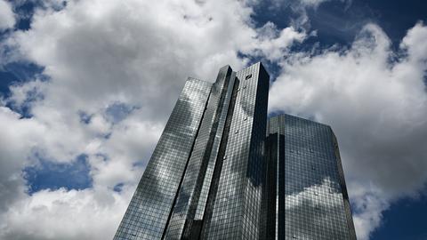 Wolken ziehen über die Zentrale der Deutschen Bank, während sich der Wolkenhimmel in der Fassade spiegelt