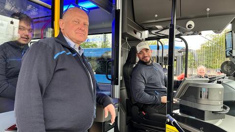 Fahrlehrer Heiko Heidenreich erklärt zwei Busfahrern die Funktionen der neuen E-Busse.