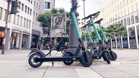 Vier E-Scooter stehen gruppiert in einer Fußgängerzone.