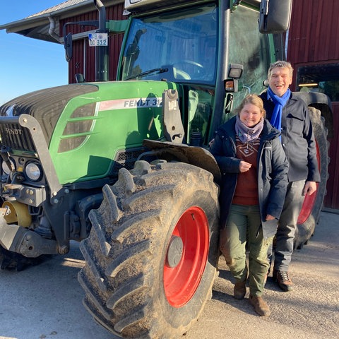 Lara Ewald, Landwirtschaftsmeisterin Biohof Ewald und Martin von Mackensen, Landwirt Dottenfelderhof - stehen lachend neben einem grünen Fendt-Traktor