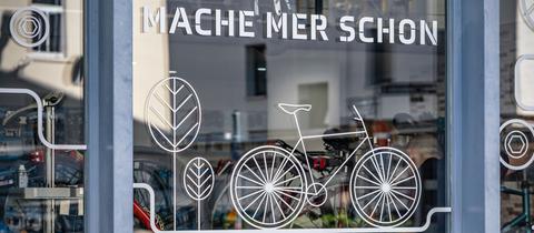 "Mache mer schon" ("Machen wir schon") steht auf hessisch am Schaufenster eines Fahrradgeschäftes am Rande der Innenstadt Frankfurts.