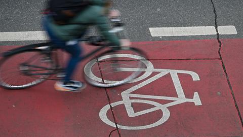 Ein Radfahrer ist in der Innenstadt auf einer roten Fahrradspur unterwegs (Aufnahme mit längerer Verschlusszeit).