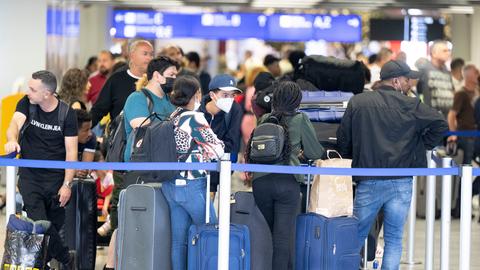 Wartende stehen am Flughafen Schlange.