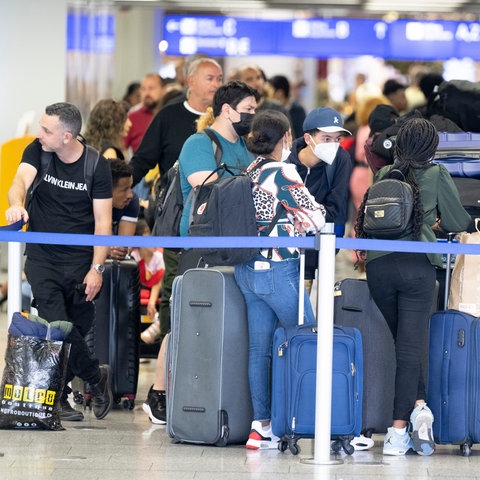 Wartende stehen am Flughafen Schlange.