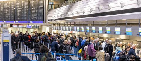 Reisende stehen an Abfertigungsschaltern im Flughafen an.
