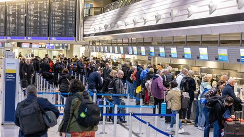 Reisende stehen an Abfertigungsschaltern im Flughafen an.