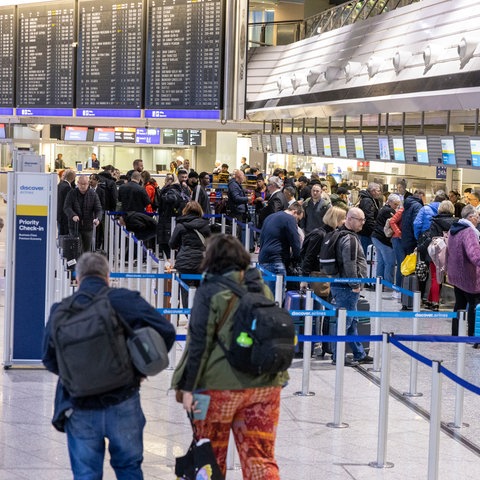 Reisende stehen an Abfertigungsschaltern im Flughafen an.
