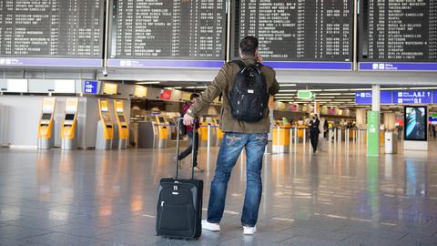Ein Mann steht mit seinem Gepäck im nahezu menschenleeren Terminal 1 des Flughafens Frankfurt. 