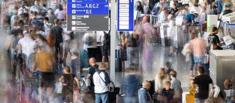 Passagiere warten vor den Abfertigungsschaltern des Frankfurter Flughafens auf ihren Check-In.