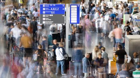 Passagiere warten vor den Abfertigungsschaltern des Frankfurter Flughafens auf ihren Check-In.