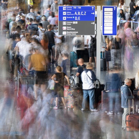 Passagiere warten vor den Abfertigungsschaltern des Frankfurter Flughafens auf ihren Check-In.