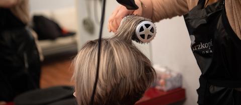 Eine Friseurin föhnt einer Kundin die Haare