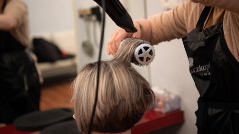 Eine Friseurin föhnt einer Kundin die Haare