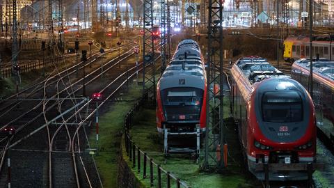 Das Bild zeigt eine Anzeigetafel an einem Bahngleis, auf der steht: GDL-Streik. Im Hintergrund sind eine S-Bahn zu sehen und eine Frau in hellblauer Winterjacke zu sehen.