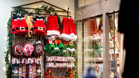 Verschiedene Weihnachtsartikel, darunter auch zahlreiche Weihnachtsmützen, stehen vor einem Geschäft zum Verkauf.