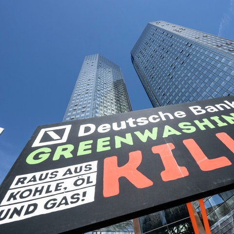 «Deutsche Bank - Greenwashing kills, raus aus Kohle, Öl und Gas!» steht auf einem Plakat, das Umweltaktivisten von Fridays for Future vor der Zentrale der Deutschen Bank aufgestellt haben.