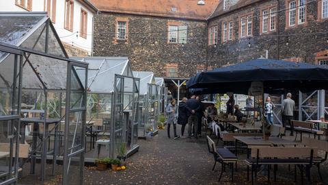 Gewächshäuser und Bierbänke in einem Gastronomiebetrieb im Fronhof in der Hanauer Innenstadt