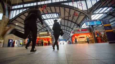Menschen gehen durch eine Bahnhofshalle.
