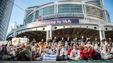 Aktivisten von "Sand im Getriebe" sitzen im Jahr 2019 in Frankfurt auf dem Boden und blockieren den Haupteingang der IAA vor dem Messegelände. 