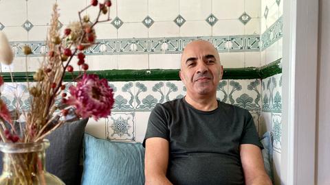 Inhaber Mehran Alvani sitzt in seinem Café Lucille in Frankfurt Nordend und lächelt. 