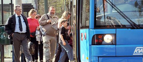Menschen steigen in einen Bus an einer Haltestelle in Kassel.