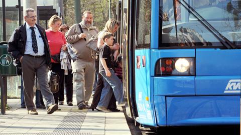 Menschen steigen in einen Bus an einer Haltestelle in Kassel.