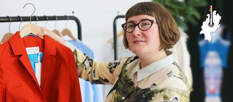 Designerin Galatea Ziss hält eine rote Jacke ihrer Kollektion hoch.