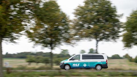 Ein elektrischer Kleinbus des Betreibers Knut fährt im Frankfurter Norden auf einer Straße mit Bäumen.