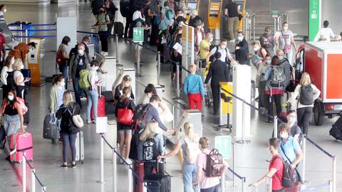 Menschen mit Koffern warten in einer langen Schlange in einer Flughafenhalle.